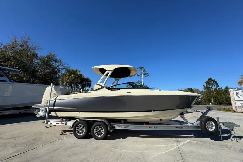 Slide: The Image of 2026 Chris-Craft Sportster 28 boat on trailer, parked outdoors under clear blue sky. - 10