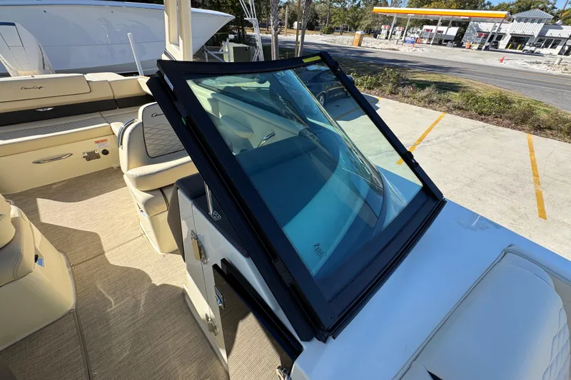 Slide: The Image of 2026 Chris-Craft Sportster 28 boat interior with seating and windshield, parked outdoors. - 24