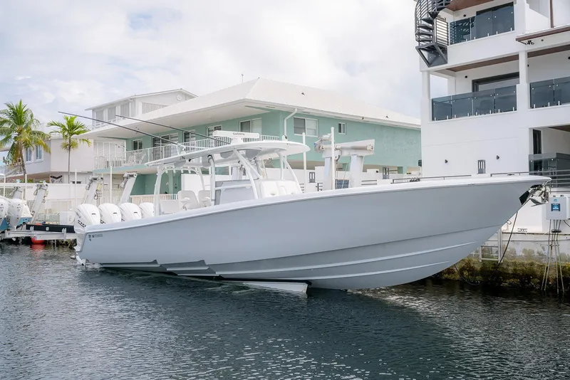 The Image of 2024 Contender 44 ST boat docked near waterfront homes under a cloudy sky. - 11