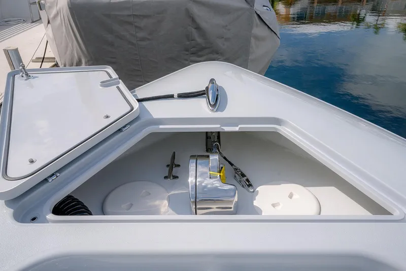 Slide: The Image of 2024 Contender 44 ST boat anchor compartment with open hatch, docked by calm water. - 46