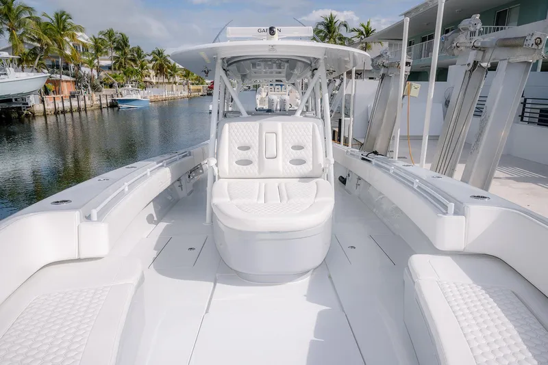 Slide: The Image of 2024 Contender 44 ST boat with luxurious white seating, docked by palm trees. - 47