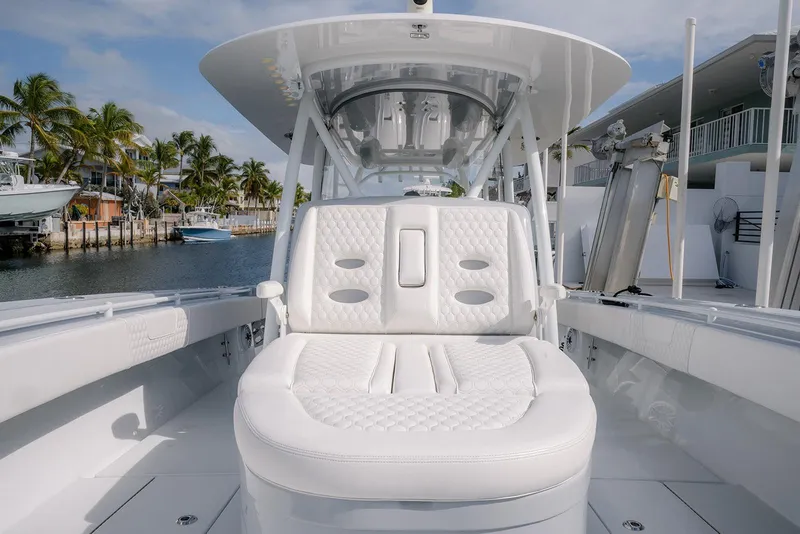 Slide: The Image of 2024 Contender 44 ST boat with luxurious white seating, docked near palm trees. - 57