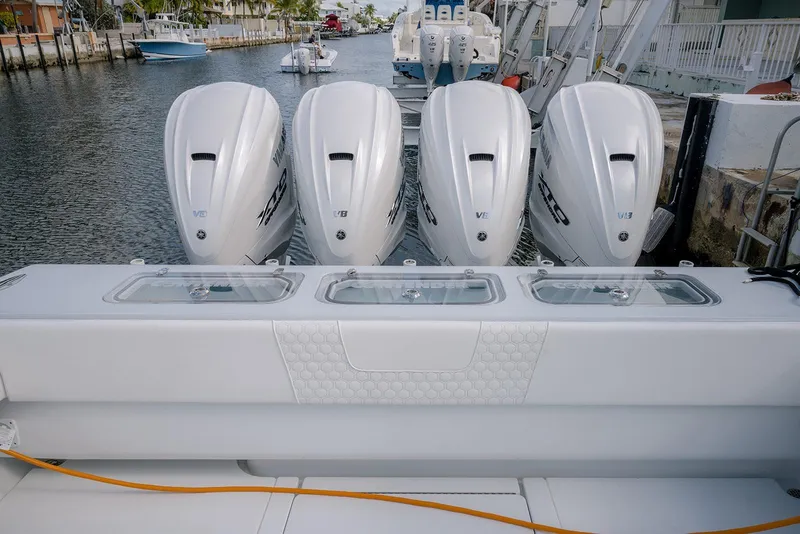 Slide: The Image of 2024 Contender 44 ST boat with four powerful outboard engines docked by the water. - 60