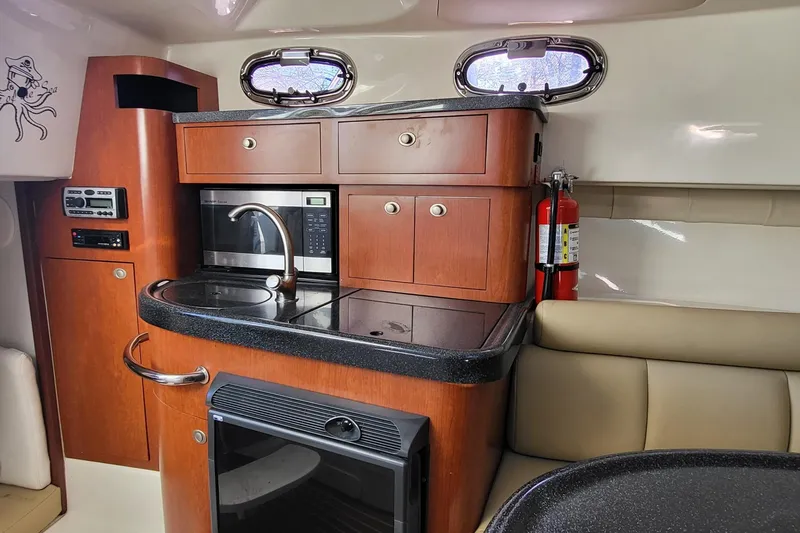 Slide: The Image of 2008 Boston Whaler 305 Conquest interior kitchen with microwave, sink, and fire extinguisher. - 15