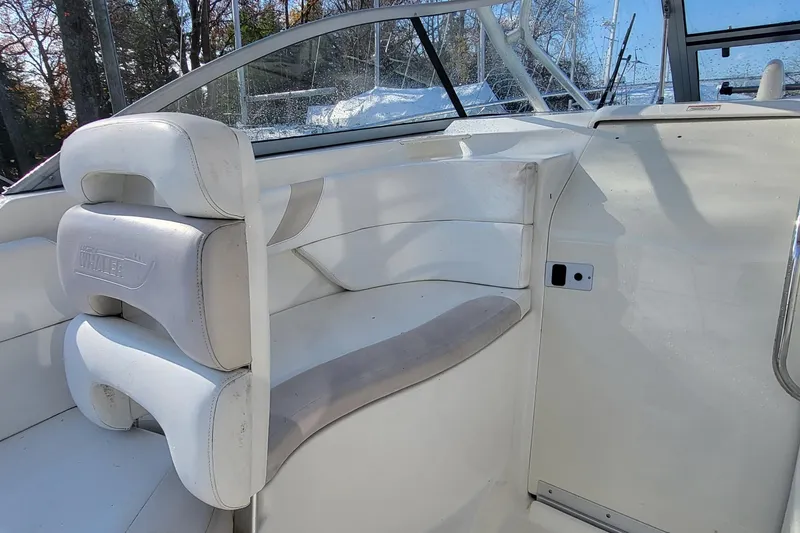 Slide: The Image of 2008 Boston Whaler 305 Conquest interior seating with white upholstery and window view. - 7