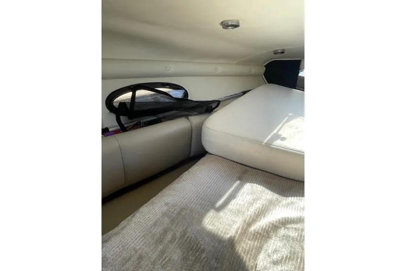 Slide: The Image of Interior cabin of 1998 Chaparral 2835 SS boat, featuring cushioned seating and small window. - 13