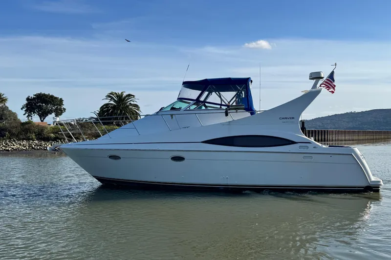 Slide: The Image of 1997 Carver 350 Mariner yacht on calm water, with American flag, clear sky background. - 3