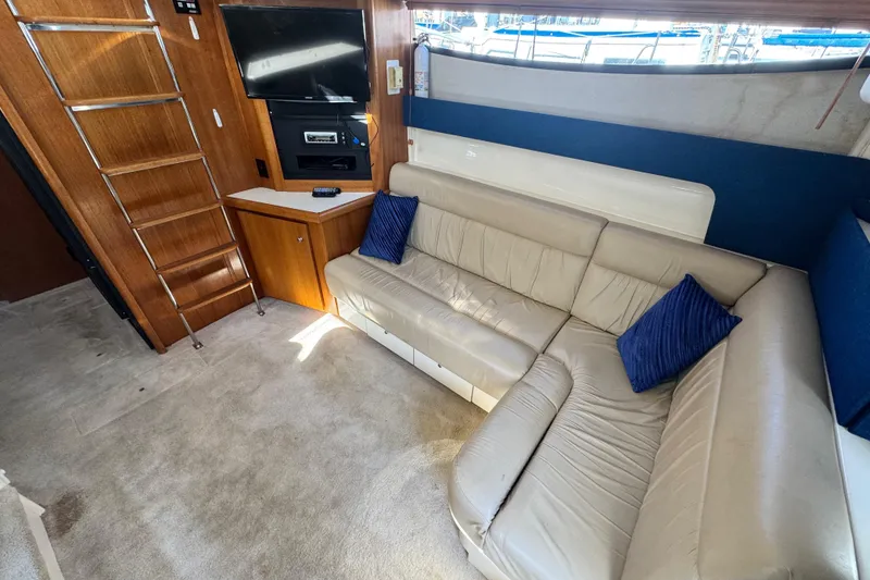 Slide: The Image of 1997 Carver 350 Mariner interior with beige sofa, blue cushions, TV, and wooden cabinetry. - 9