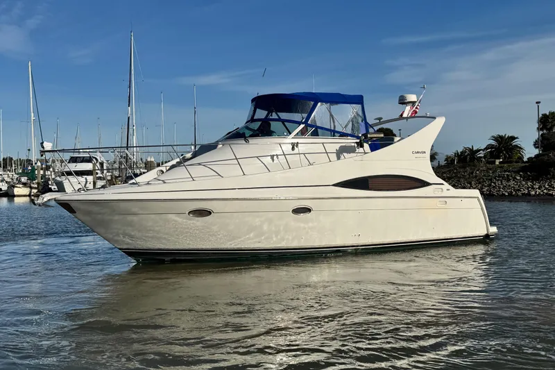 The Image of 1997 Carver 350 Mariner yacht docked in a marina under clear blue skies. - 1