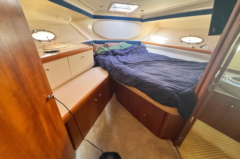 Slide: The Image of 1997 Carver 350 Mariner cabin interior with bed, wooden cabinetry, and portholes. - 12