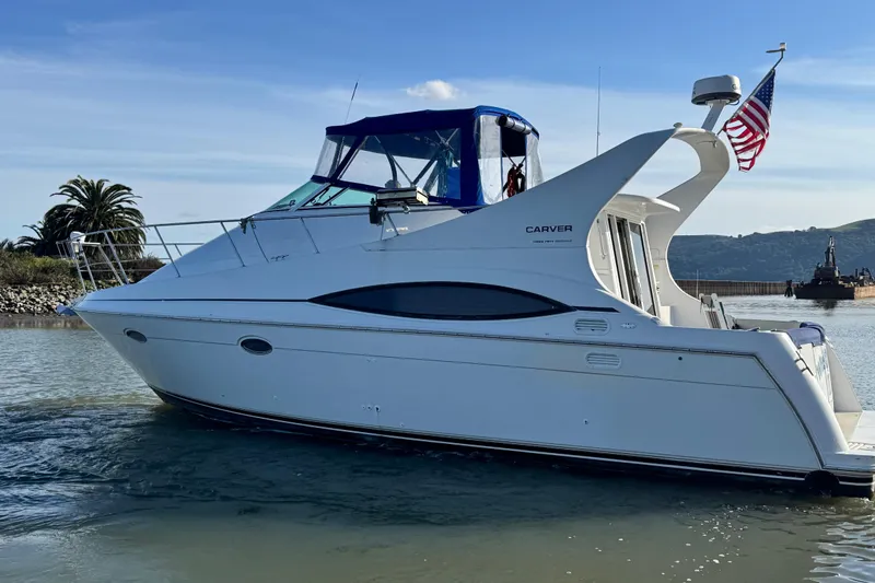 Slide: The Image of 1997 Carver 350 Mariner yacht on calm water, American flag, clear sky. - 2