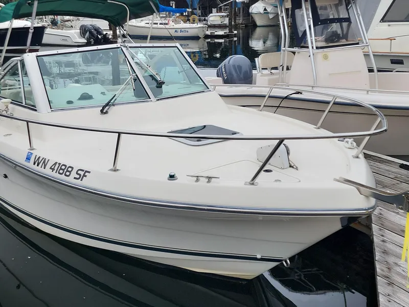 Slide: The Image of 1999 Pursuit 2460 Danali boat docked in marina, white exterior, green canopy. - 1