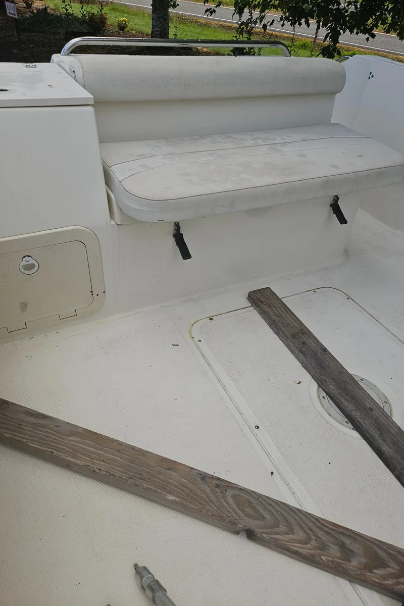 Slide: The Image of 1999 Pursuit 2460 Denali boat interior with white seating and wooden planks. - 11