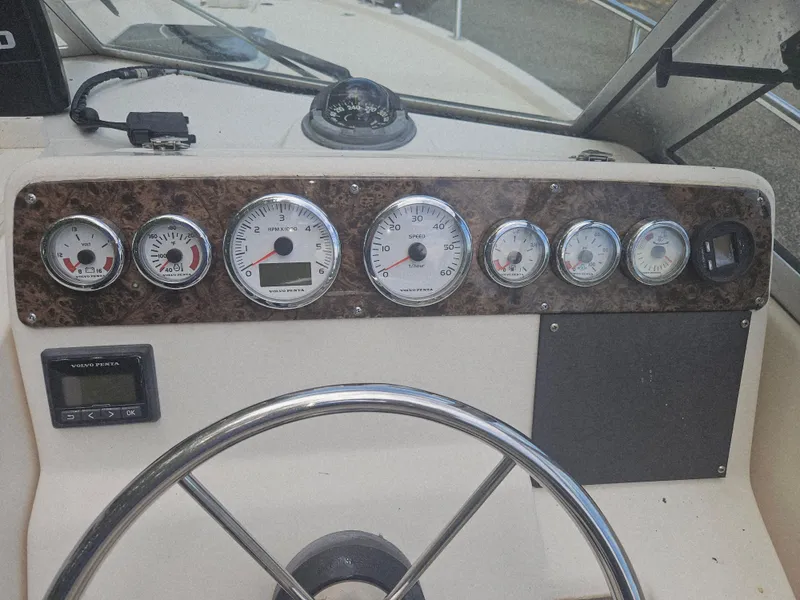 Slide: The Image of Dashboard of a 1999 Pursuit 2460 Denali boat with gauges and steering wheel. - 7