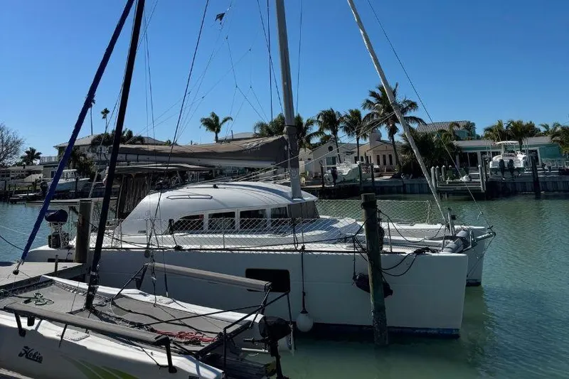 The Image of 2006 Lagoon 380 catamaran docked in a sunny marina with palm trees. - 0