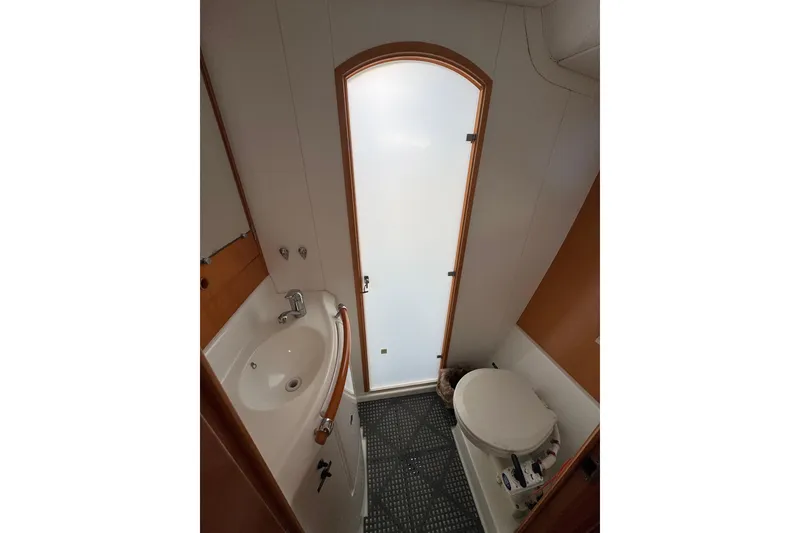 Slide: The Image of Bathroom interior of 2006 Lagoon 380 catamaran with sink, toilet, and frosted door. - 16