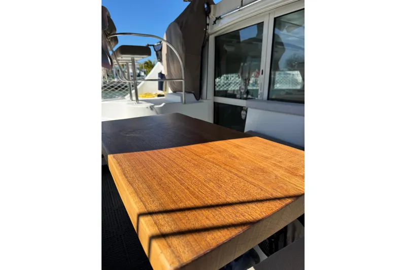 Slide: The Image of Wooden table on 2006 Lagoon 380 catamaran deck, with seating and windows in view. - 2