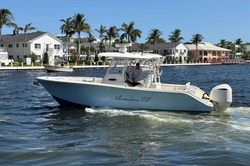 Slide: The Image of 2018 Cobia 301 Center Console boat cruising on a sunny waterfront with palm trees. - 11