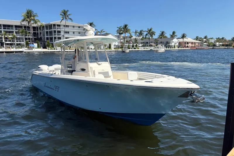 Slide: The Image of 2018 Cobia 301 Center Console boat on water near waterfront buildings and palm trees. - 12