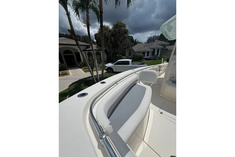 Slide: The Image of 2018 Cobia 301 Center Console boat with white seating, parked near residential homes. - 19