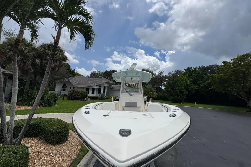 Slide: The Image of 2018 Cobia 301 Center Console boat parked in a residential driveway, surrounded by lush greenery. - 21