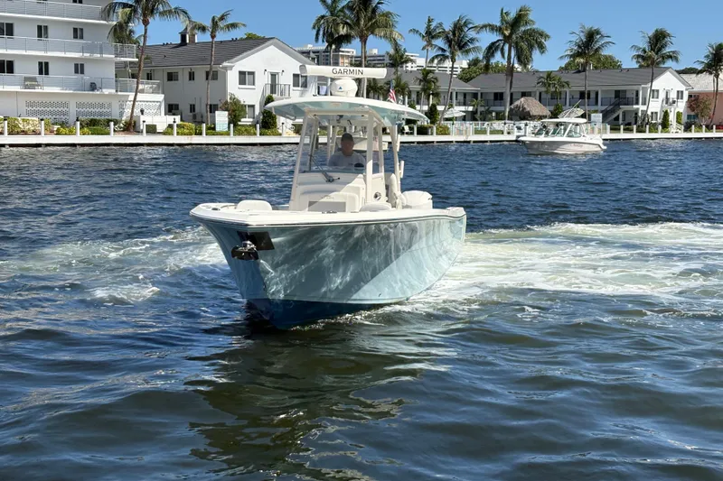 Slide: The Image of 2018 Cobia 301 Center Console boat cruising on a sunny waterfront with palm trees. - 3