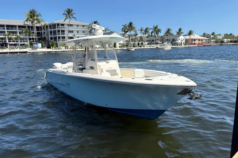 Slide: The Image of 2018 Cobia 301 Center Console boat cruising on a sunny waterfront with palm trees. - 5
