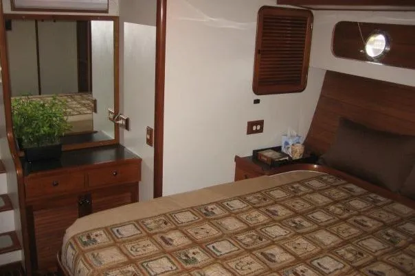 Slide: The Image of Cozy bedroom interior of 1990 Nordhavn 46 yacht with wooden accents and patterned bedding. - 12