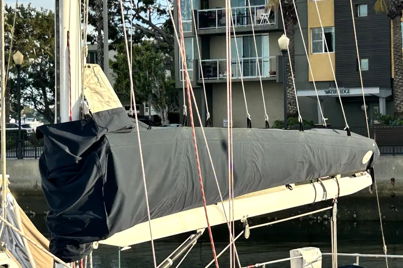 Slide: The Image of 1969 Hinckley 38 sailboat with covered boom, docked near modern apartments. - 11