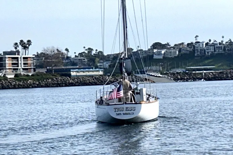 Slide: The Image of Hinckley 38 sailboat from 1969, named "Tigress," sailing near a coastal marina. - 14