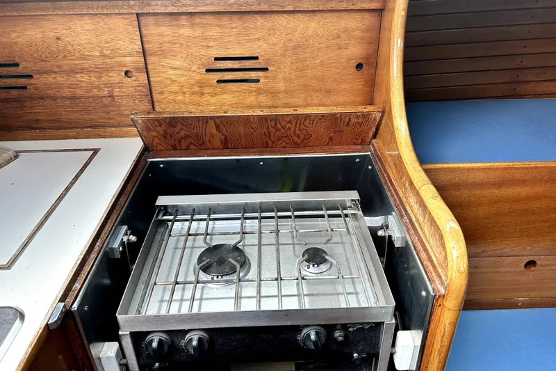 Slide: The Image of Vintage 1969 Hinckley 38 yacht interior with wooden cabinetry and a compact stove. - 26