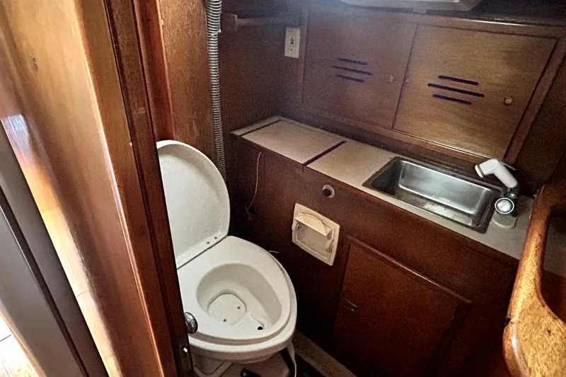 Slide: The Image of Hinckley 38 (1969) boat bathroom with toilet, sink, and wooden cabinetry. - 31