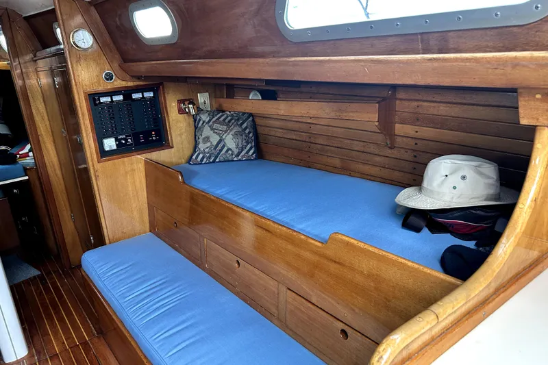 Slide: The Image of Interior of a 1969 Hinckley 38 sailboat with wooden paneling and blue cushions. - 21
