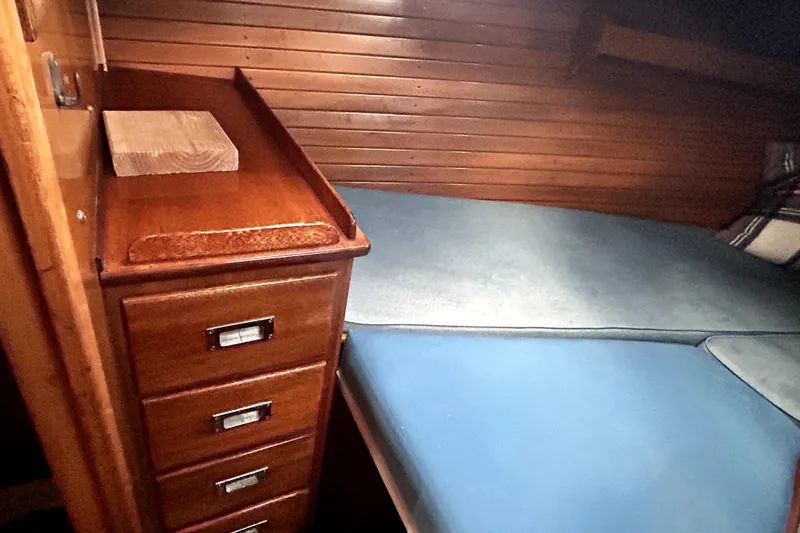 Slide: The Image of Wooden interior of a 1969 Hinckley 38 sailboat with blue cushions and storage drawers. - 30