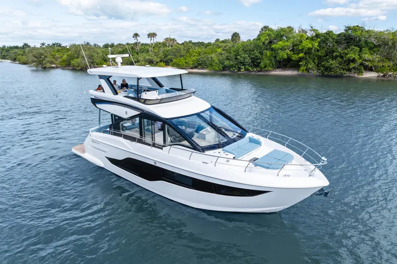 Slide: The Image of 2026 Cruisers 50 Fly yacht cruising on a serene waterway with lush greenery. - 12