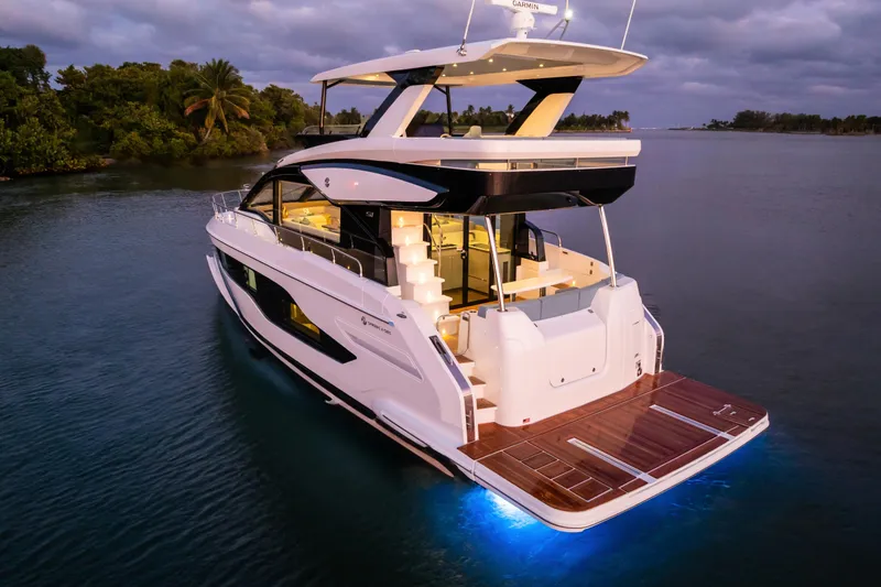 Slide: The Image of 2026 Cruisers 50 Fly yacht illuminated on serene water at dusk. - 9