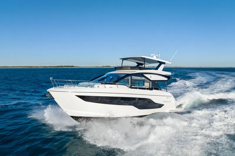 The Image of 2026 Cruisers 50 Fly yacht cruising on open water under clear blue sky. - 0