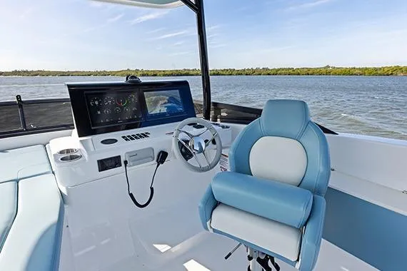 Slide: The Image of 2026 Cruisers 50 Fly yacht helm with modern controls and blue seating on open water. - 15