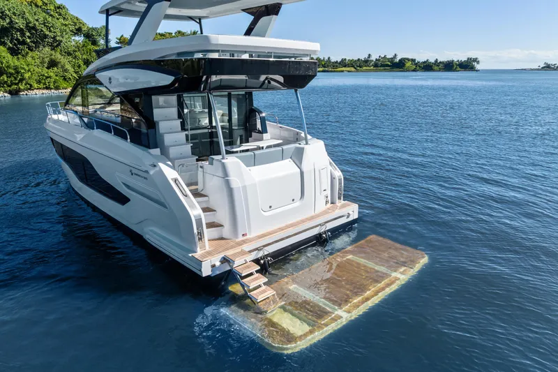 Slide: The Image of 2026 Cruisers 50 Fly yacht on serene water with extended swim platform. - 21