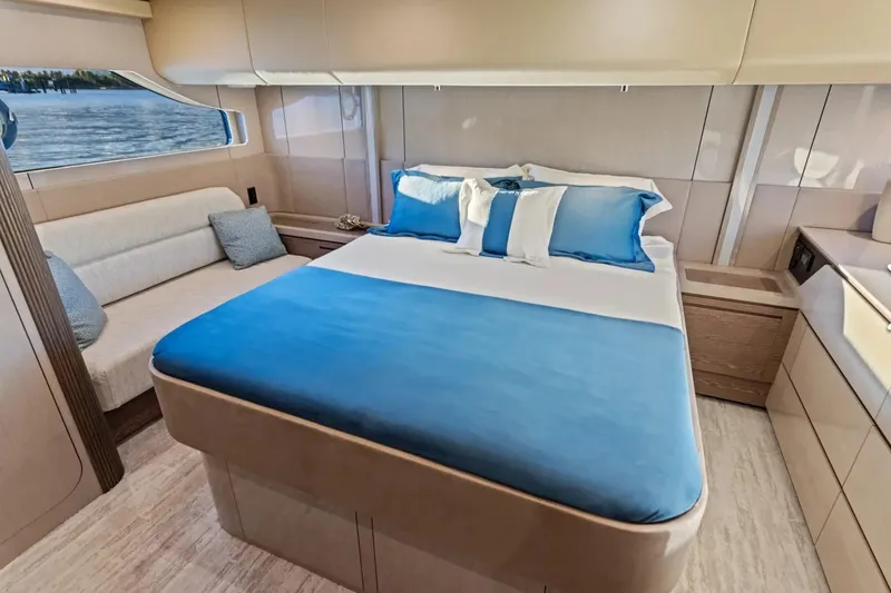 Slide: The Image of Luxurious bedroom interior of 2026 Cruisers 50 Fly yacht with blue bedding and scenic window view. - 29