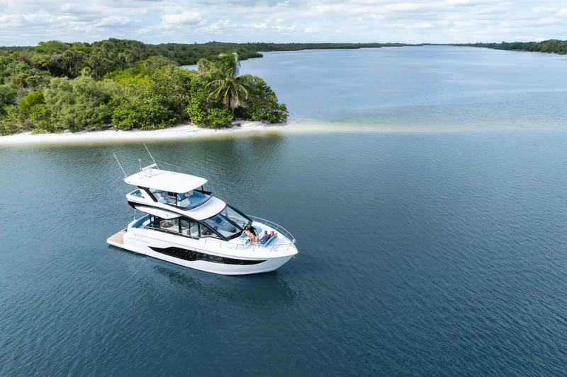 Slide: The Image of 2026 Cruisers 50 Fly yacht cruising near lush island shoreline. - 44