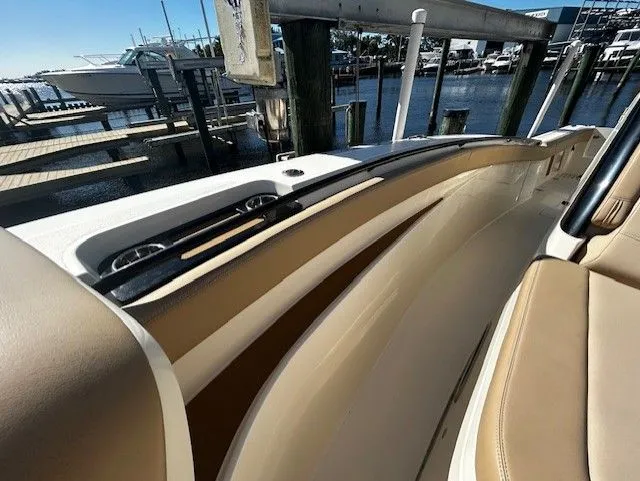 Slide: The Image of Scout 305 LXF 2022 boat, interior view with beige seats at dock. - 13