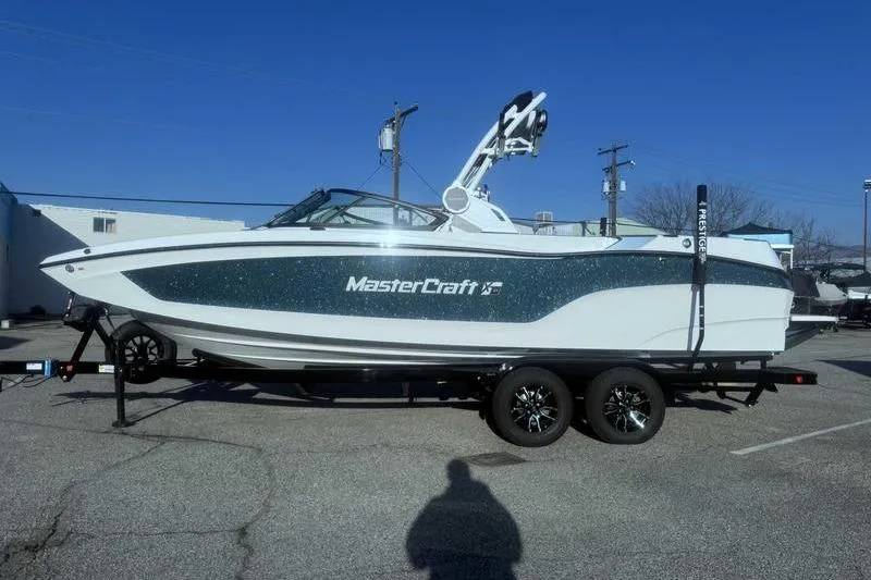 The Image of 2026 MasterCraft XT24 boat on trailer in parking lot, side view. - 1