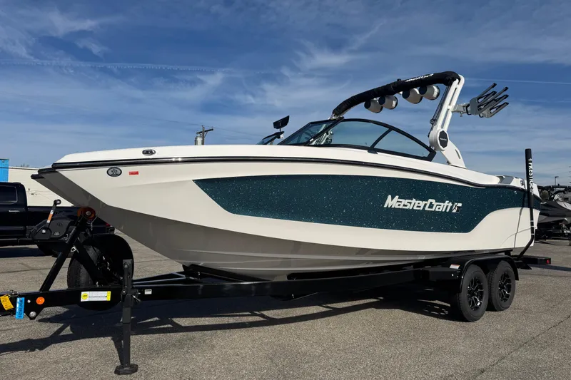 Slide: The Image of 2026 MasterCraft XT24 boat on trailer under clear blue sky. - 3
