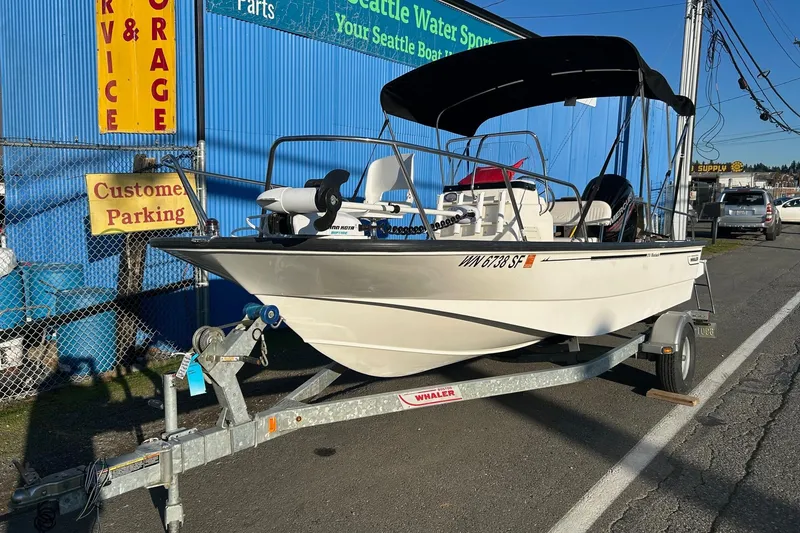 Slide: The Image of 2015 Boston Whaler 170 Montauk boat on trailer, parked outside a blue building. - 9