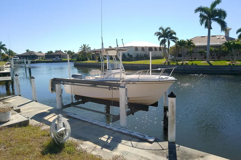 The Image of 1999 Grady-White Escape 209 boat on lift by canal, surrounded by palm trees. - 0