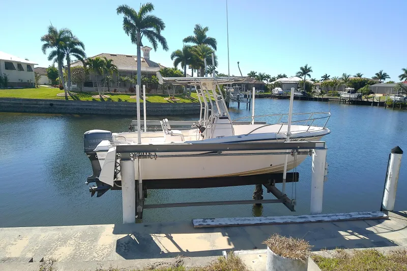Slide: The Image of 1999 Grady-White Escape 209 boat on lift by canal, surrounded by palm trees. - 1