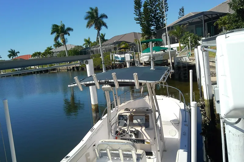Slide: The Image of 1999 Grady-White Escape 209 boat docked in a scenic waterfront area with palm trees. - 11