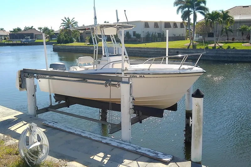 Slide: The Image of 1999 Grady-White Escape 209 boat on lift by waterfront homes. - 2