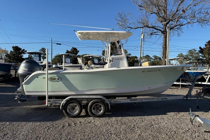 Slide: The Image of 2018 Sea Hunt Ultra 225 boat on trailer, parked outdoors under clear blue sky. - 10